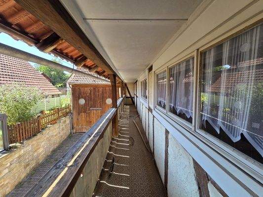 Überdachter Balkon mit Zugang zu zwei Zimmern und dem Dachboden