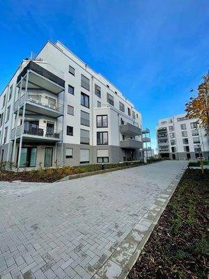 Rückansicht des Gebäudes Vincent-van-Gogh-Ring 63 mit Balkonen, weiße Fassade, 5 Geschosse + Staffelgeschoss