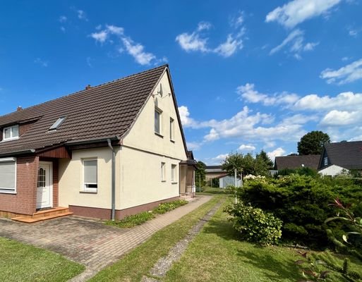 Blick auf Haus und Garten mit Veranda, praktischem Nebeneingang und Garage