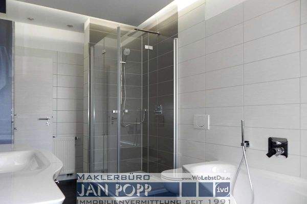 Tageslichtbad mit Eckwanne, Duschkabine und Badmöbeln  