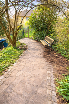 Sonniger Gartenweg mit Bank