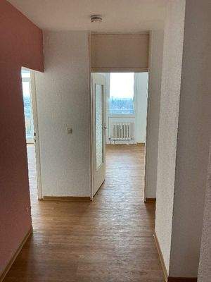 Flur mit weißen und rosa Wänden, Design-Vinylboden in Holzoptik, sowie Zugang zu weiteren Zimmern,