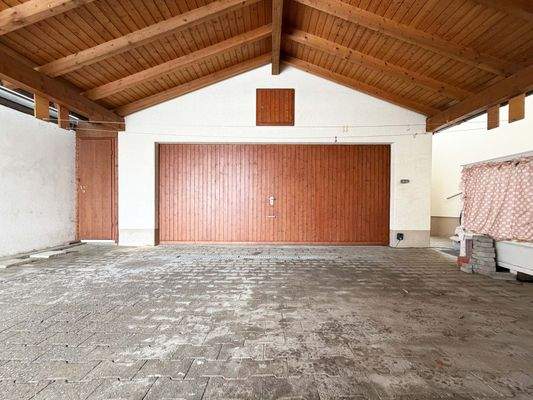 Überdachte Zufahrt und Stellplatz vor der großen Doppelgarage