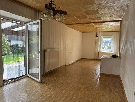 Das Wohnzimmer mit Tür zur Terrasse und den Garten