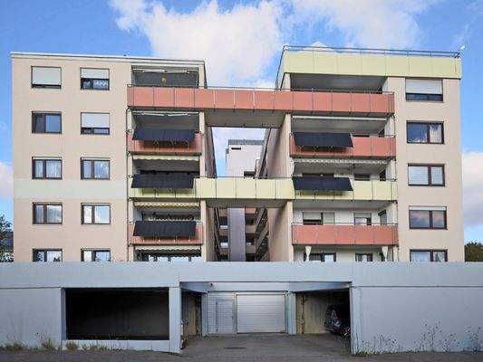 Hausansicht mit Tiefgarageneinfahrt und überdachten Stellplätzen