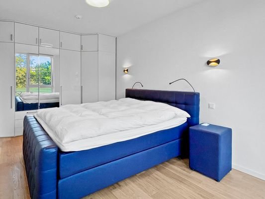 Gemütliches Schlafzimmer mit großem Boxspringbett und Kleiderschrank