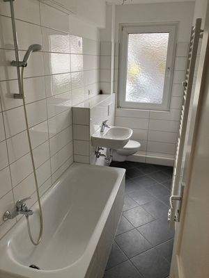 modernes Tageslichtbad mit weißen Fliesen an den Wänden und dunklen Fliesen am Boden.jpg