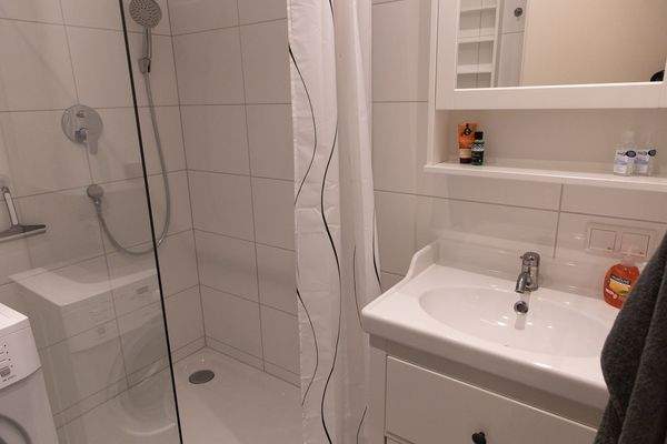 Badezimmer mit geräumiger Dusche. Waschmaschine ist vorhanden. Die Toilette befindet sich in einem separaten Raum.