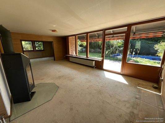 Wohnzimmer mit Holzofen und Blick in den Garten