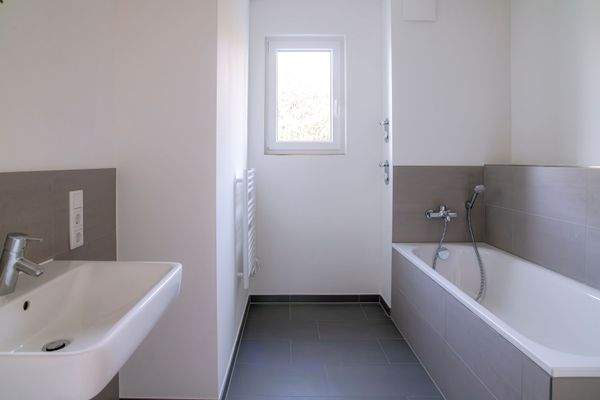 Blick in das Bad mit Wanne und Fenster