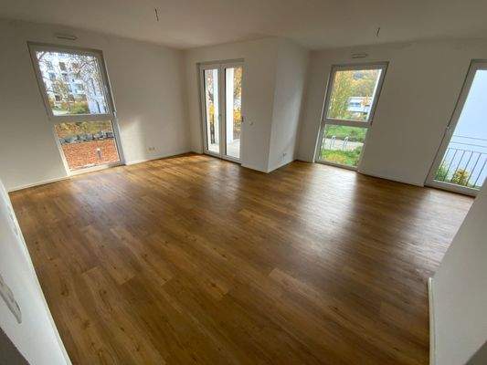 Wohn- und Essbereich mit weißen Wänden, Vinylboden in Holzoptik und Fenstern.JPG