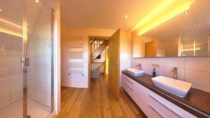 Modernes Badambiente mit ebenerdiger Dusche und stilvoller Ausstattung für höchsten Komfort