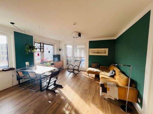 Wohn- und Essbereich, grüne Wände, Boden in Holzoptik, gut beleuchtet, Fenster.jpeg