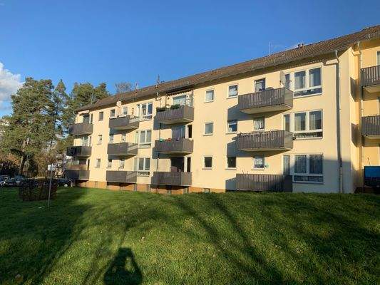 Außenansicht des Haues mit Bäumen vor der Tür und Balkonen an jeder Wohnung 