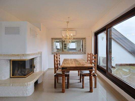 Essbereich mit Kamin und Zugang zur Loggia