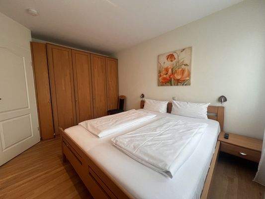 Geräumiges Schlafzimmer mit integriertem Kleiderschrank und moderner Beleuchtung