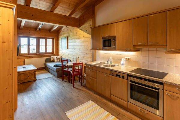 Offene Wohnküche mit Essbereich, Sofa und viel Holzambiente für gemütliche Stunden.