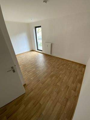 Schlafzimmer mit weißen Wänden, hellbraunem PVC Boden in Holzoptik und bodentiefem Fenster.jpg