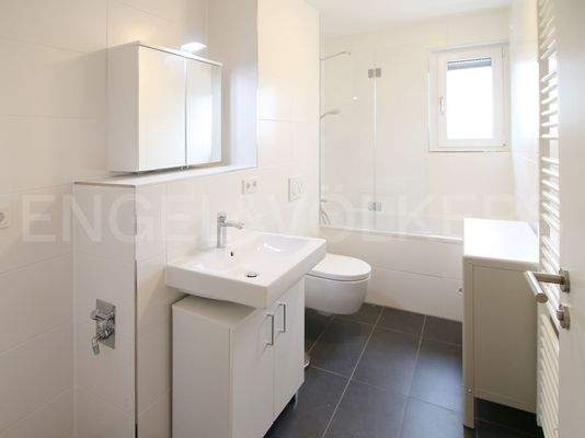 Badezimmer mit Waschmaschinenanschluss und Duschwand an der Badewanne