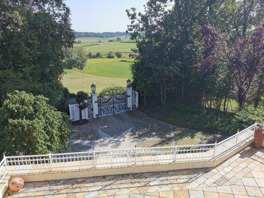 Terrassenblick auf das schmiedeeiserne Eingangstor und weite Landschaftspanoramen