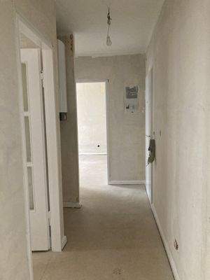 Flur mit Zugang zu allen Zimmern mit weißen Türen und tapetenlosen Wänden.