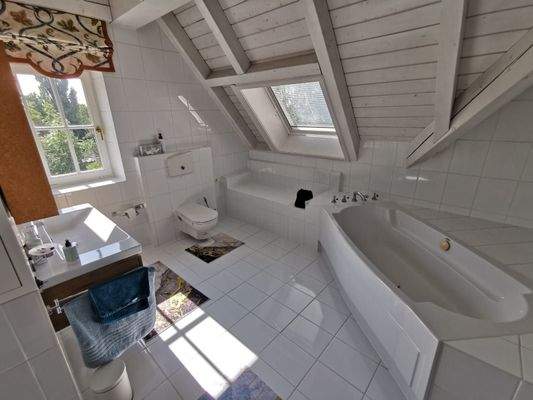 EG: Modernes Badezimmer mit Badewanne unter Dachschräge und viel Tageslicht.