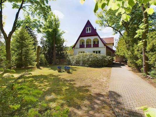 Hausansicht von vorne mit Blick in den großzügigen Vorgarten und auf die Einfahrt