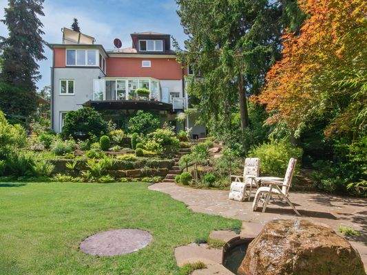 Hausansicht vom unteren Garten aus mit Terrasse und Brunnen