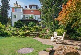 Hausansicht vom unteren Garten aus mit Terrasse und Brunnen