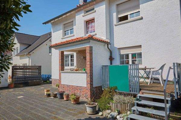 Gepflasterter Außenbereich mit überdachtem Eingangsportal und direktem Terrassenzugang