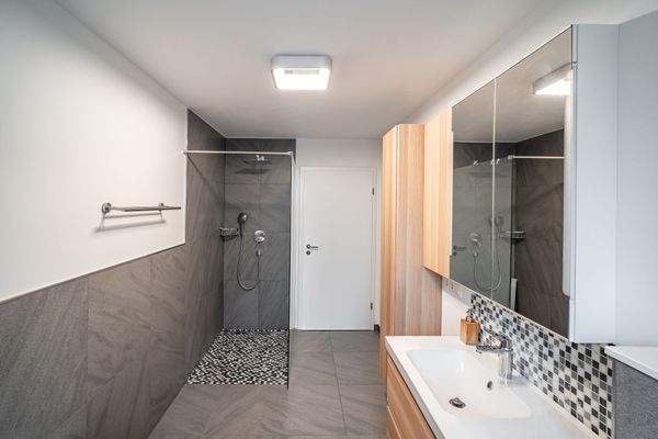 Der Raum ist mit einer Wanne und einer bodengleichen Glasdusche ausgestattet.