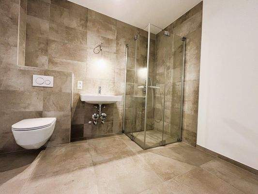 Badezimmer mit WC, Waschbecken, Walk-In-Dusche und Waschmaschinenanschluss