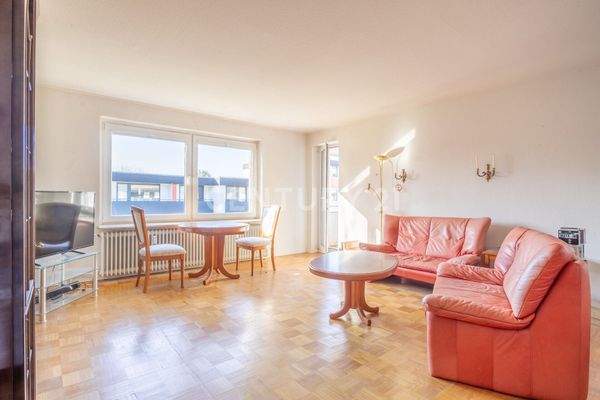 Wohnzimmer mit Parkettboden und Zugang zum Balkon