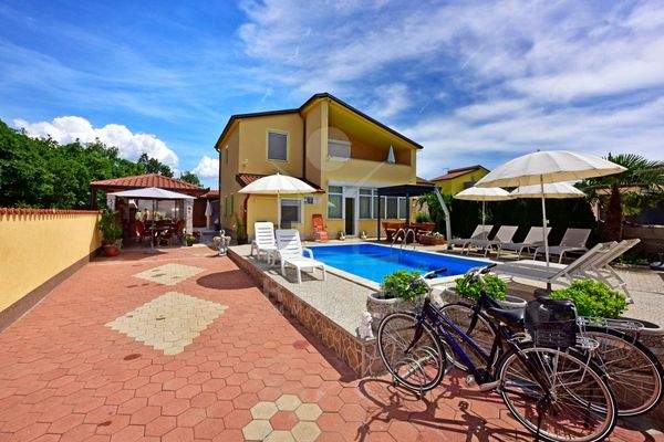 [g] Mediterrane Terrasse zum Entspannen und Genießen ~ Die Außenanlage der Villa lädt zu entspannten Stunden im Freien ein. Ein 24 m² großer Pool mit Außendusche bietet Erfrischung, während Liegestühle rundherum zum Sonnenbaden einladen. Ein überdachter B