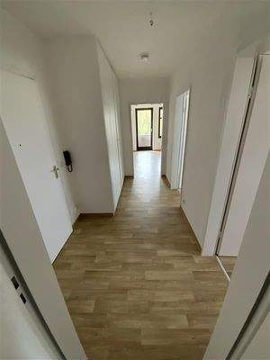 Eingangsbreich und Flur mit weißen Wänden, weißen Türen und hellbraunem PVC Boden in Holzoptik.jpg