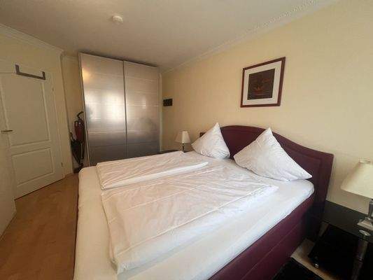 Geräumiges Schlafzimmer mit großzügigem Bett und integriertem Stauraum