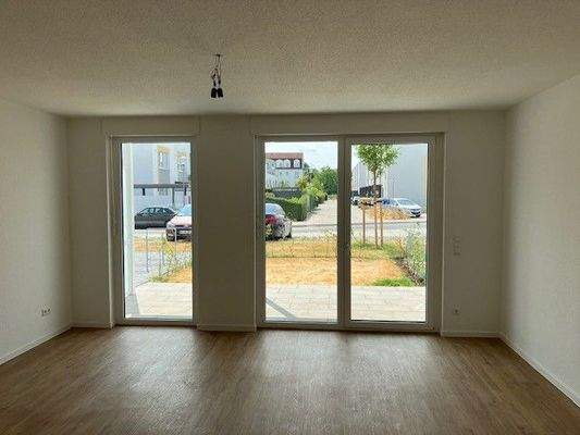 Wohnzimmer mit Blick auf die Terrasse und kleinem Garten. Weiße Wände, brauner Vinyl-Designboden in Holzoptik