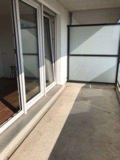 Blick vom Wohnraum auf den Balkon mit Glasbalkonbrüstung mit Trennwand aus Glas und grauem Boden