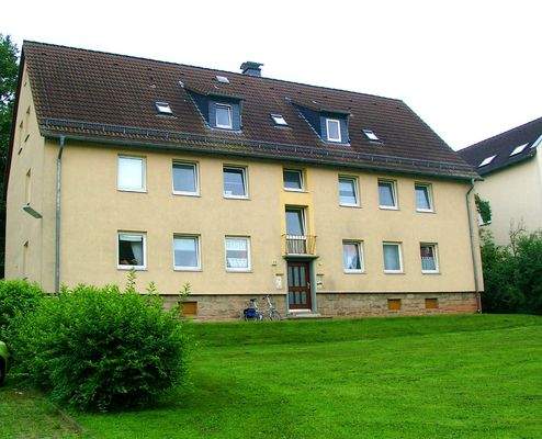 Blick auf das zweistöckige Mehrfamilienhaus mit Rasenfläche vor der Haustür 