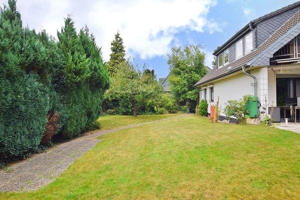 Rasen umrahmt das Haus - zu den Grenzen ist der Garten schön eingewachsen