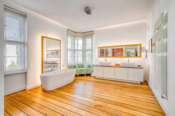 Helles Wohfühlbad mit Freistehwanne, stilvollem Doppelwaschtisch und maritim anmutenden Schiffsbodendielen