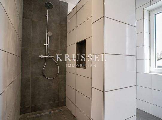 Modernes Badezimmer mit ebenerdiger Dusche und zeitgemäßer Ausstattung für höchsten Komfort