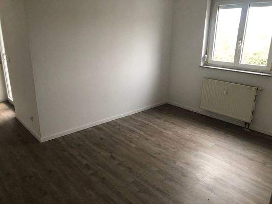 Wohnzimmer mit Zugang zu Balkon, Laminatboden, weiße Wände.JPG