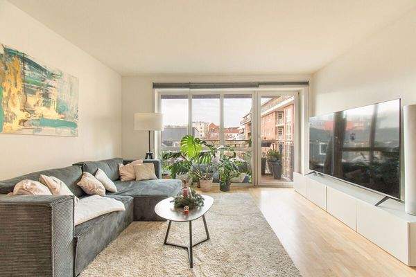 Gemütliches Wohnzimmer mit großer Fensterfront und Zugang zum Balkon