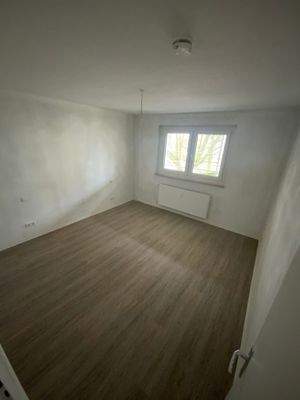 Schlafzimmer mit weiß grundierten Wänden, Fenster und Designerboden in Holzoptik