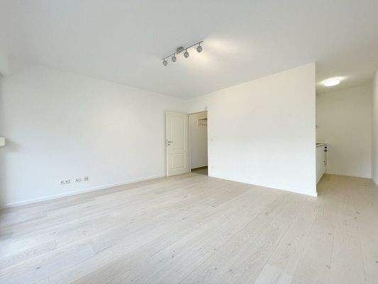 Blick in den großen hellen Wohnraum mit halboffener Küche