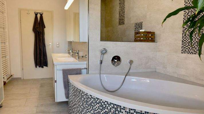 Bad mit Dusche und Badewanne und Zugang zum überdachten Balkon