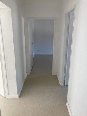 Flur mit weiß angelegten Wänden und hellem Linoleumboden