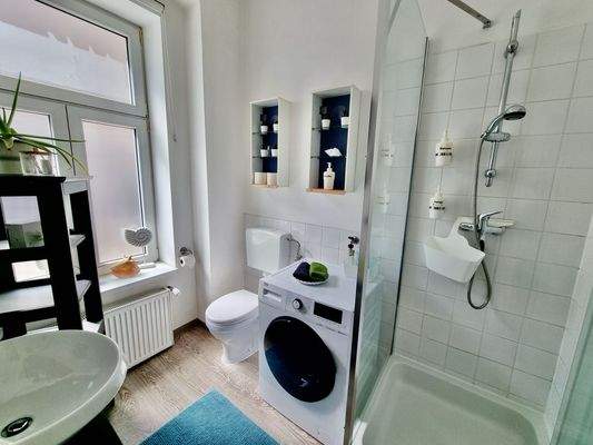 Badezimmer mit Dusche, Waschmaschine und Wäschetrockner