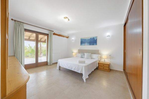 Helles und elegantes Doppelschlafzimmer mit direktem Zugang zur überdachten Terrasse und Gartenblick.